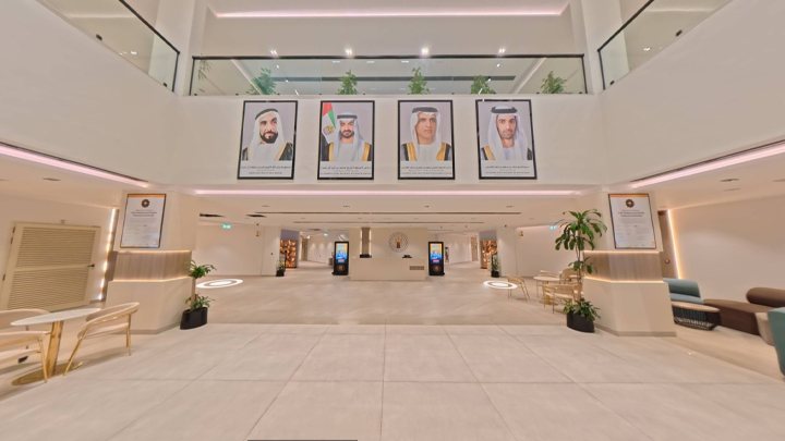 The double-height main lobby of the RAKMHSU campus, with portraits of the UAE leadership on the far wall, seating areas to either side and information kiosks along the corridor beyond