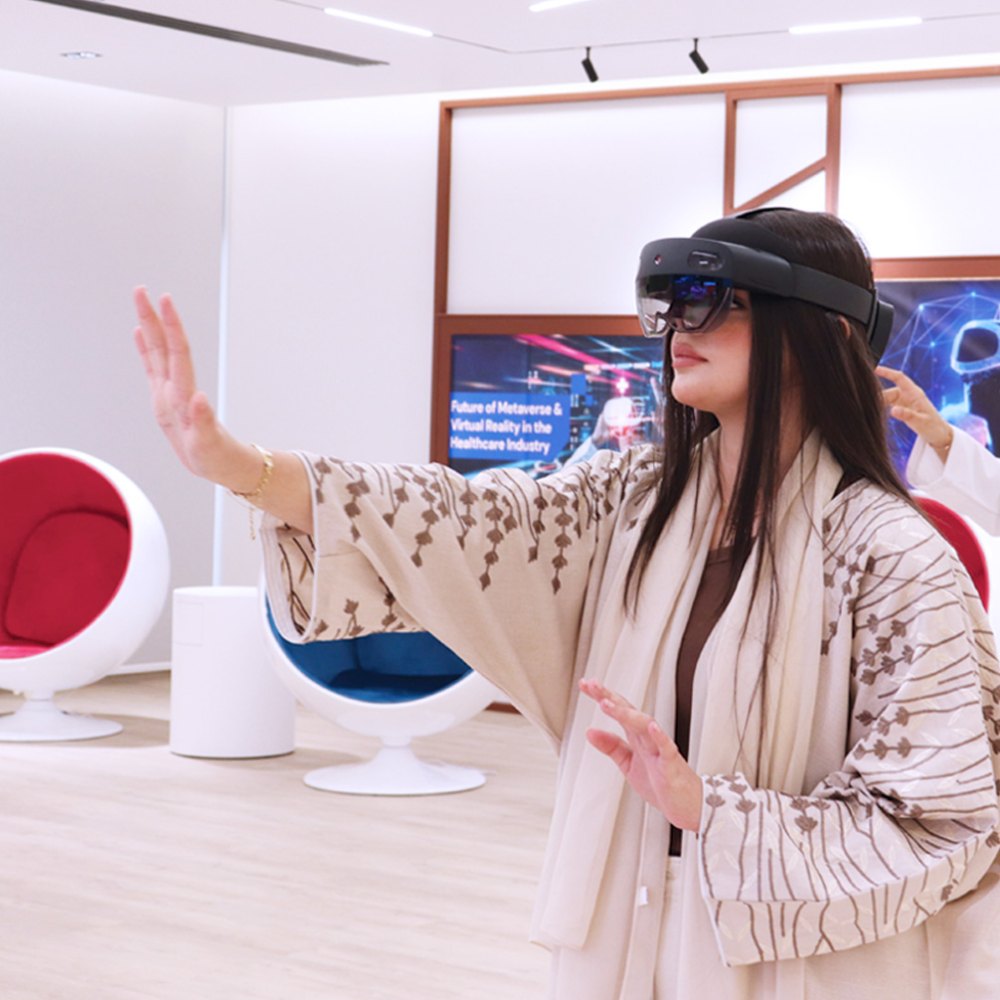A participant wearing a mixed-reality headset reaching out to interact with a virtual display, beside a screen reading Future of Metaverse & Virtual Reality in the Healthcare Industry