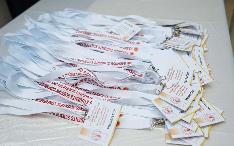 Presenter badges on lanyards printed with RAKMHSU Students Scientific Conference, laid out on the registration table