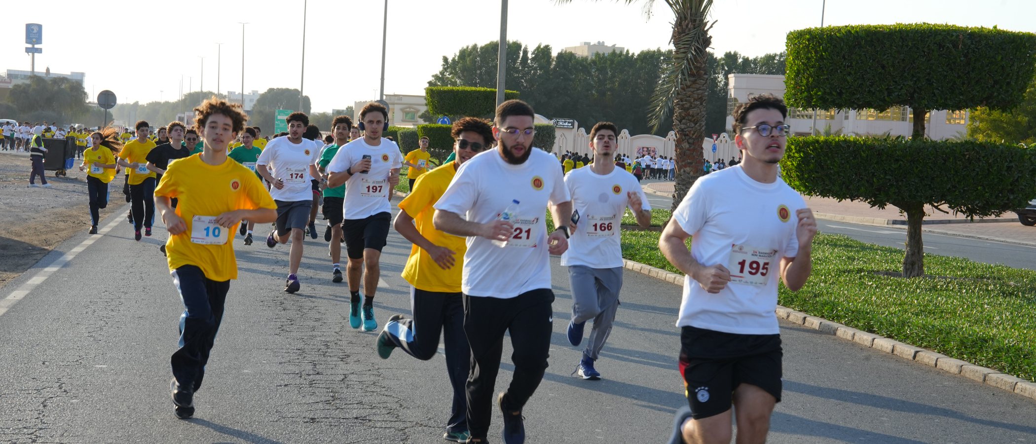 RAKMHSU students running in numbered bibs along the campus road at the University&rsquo;s Mini Marathon